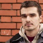 Young man looking at camera with serious face and brick wall background.