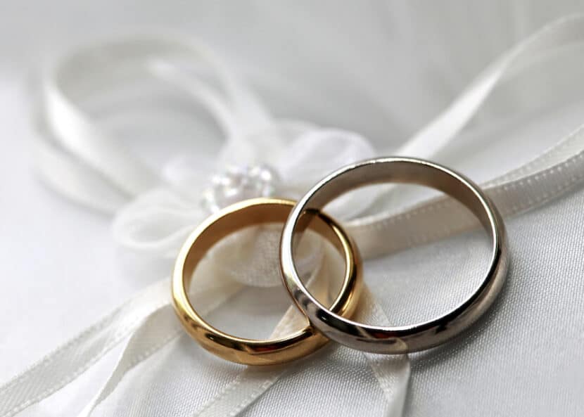 Pair of wedding bands on top of white satin.