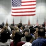 Immigration swearing in ceremony with American flag hanging in the background.