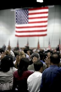 Immigration swearing in ceremony with American flag hanging in the background.